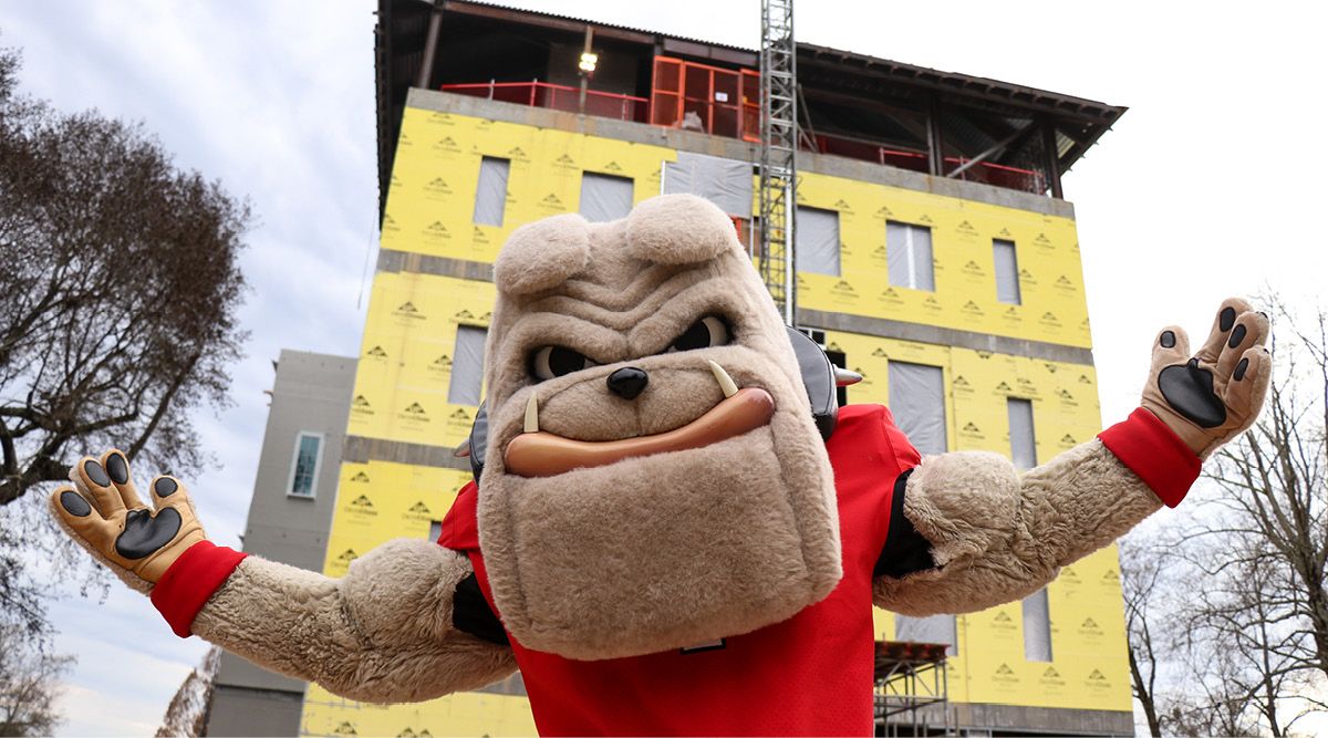 Hairy Dawg in front of the construction site where the poultry science building is under construction.