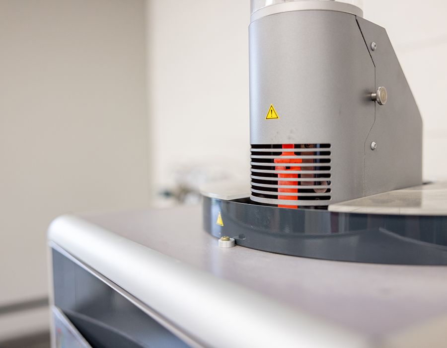 A small metal piece glows red orange with heat inside of a countertop machine.