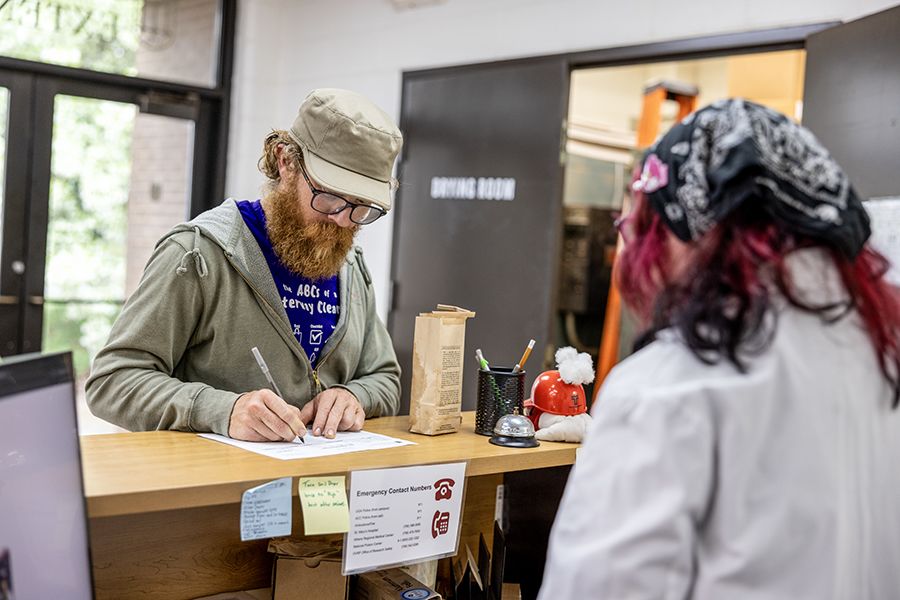 Man fills out paperwork at a counter, helped by lab assistant