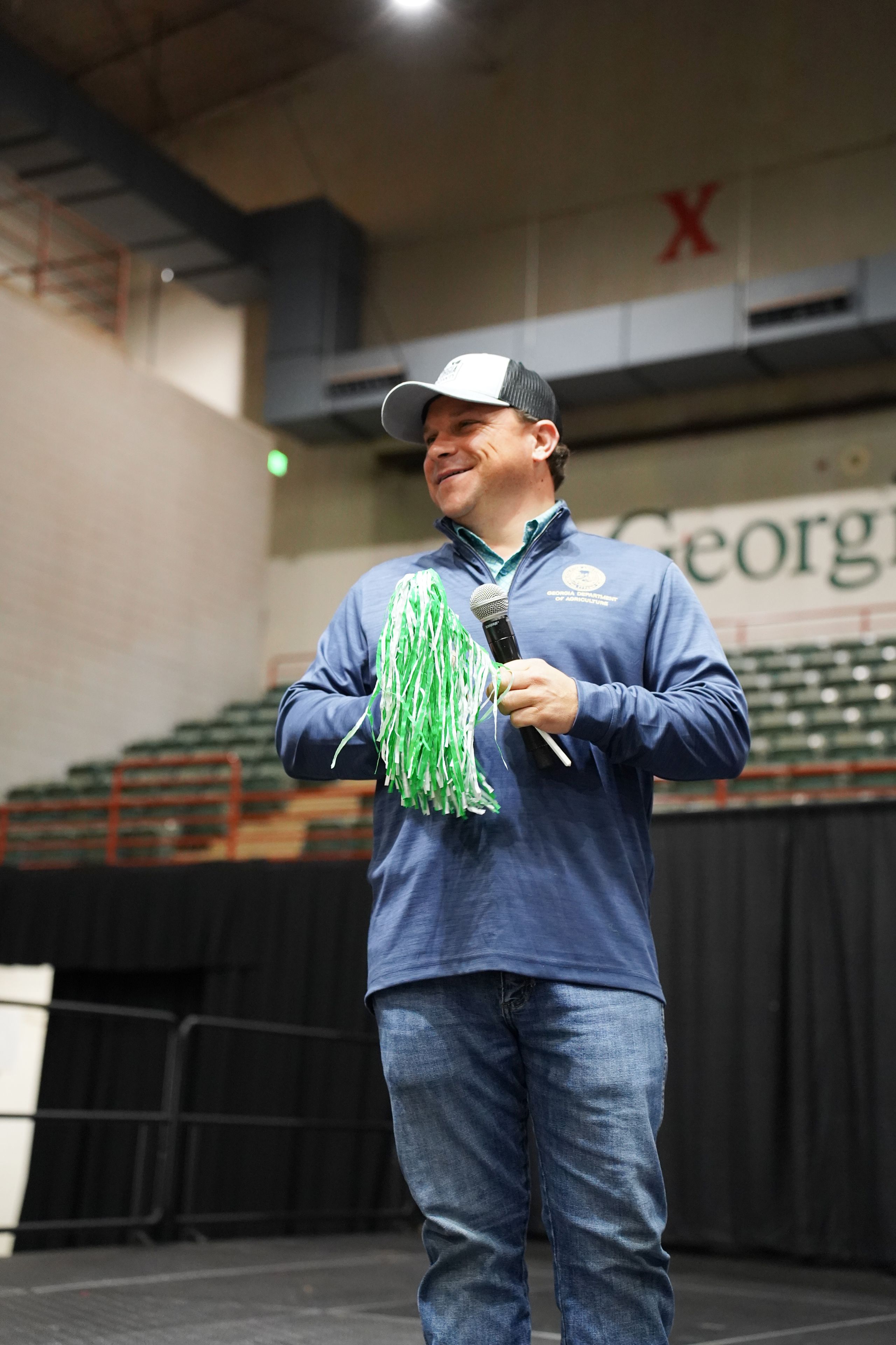 Georgia Agriculture Commissioner Tyler Harper holds a green and white pom pom at 4-H Day at the Fair. 