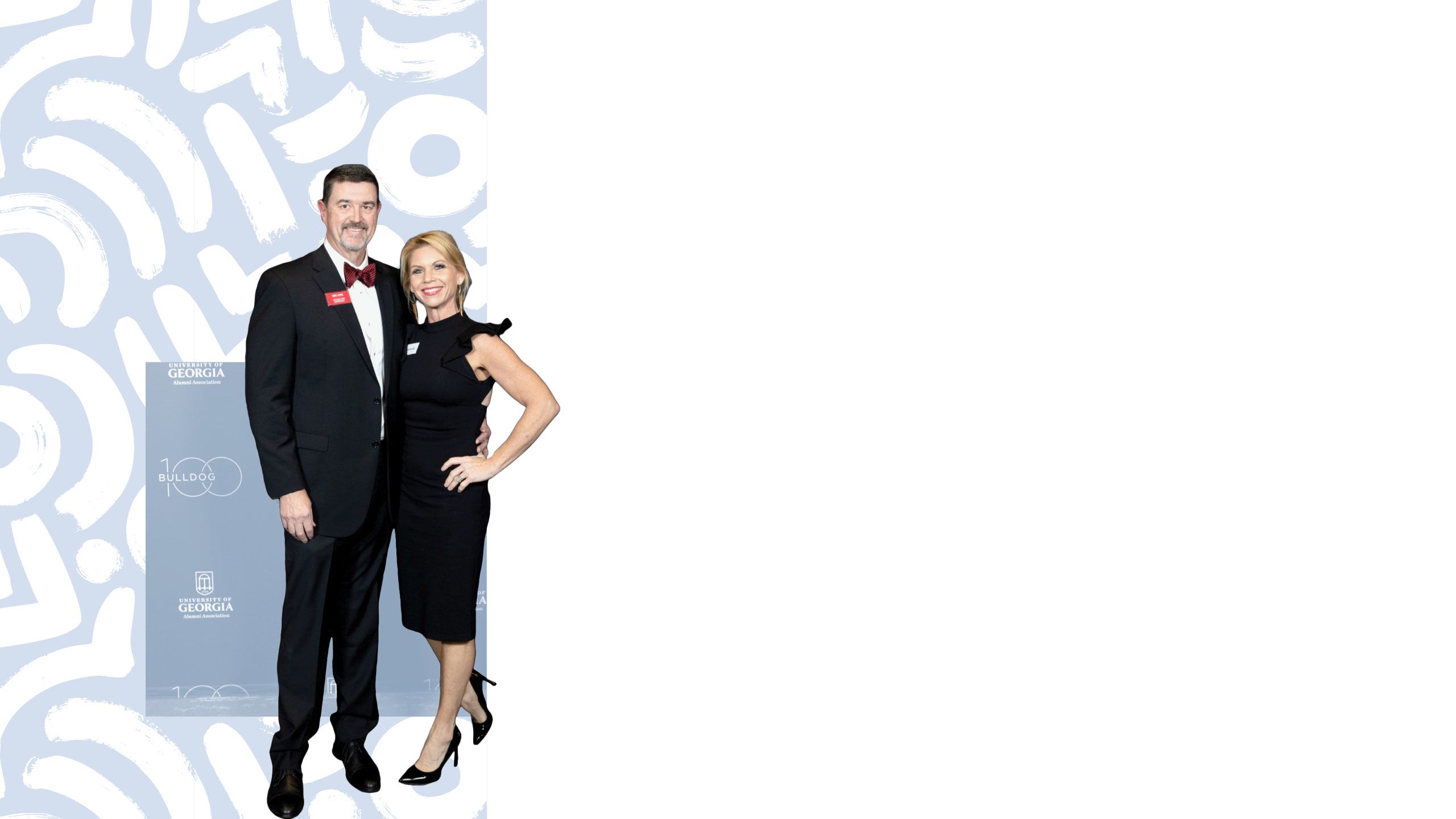 Mike Lewis stands with his wife, both dressed in formal attire, in front of a Bulldog 100 sign.