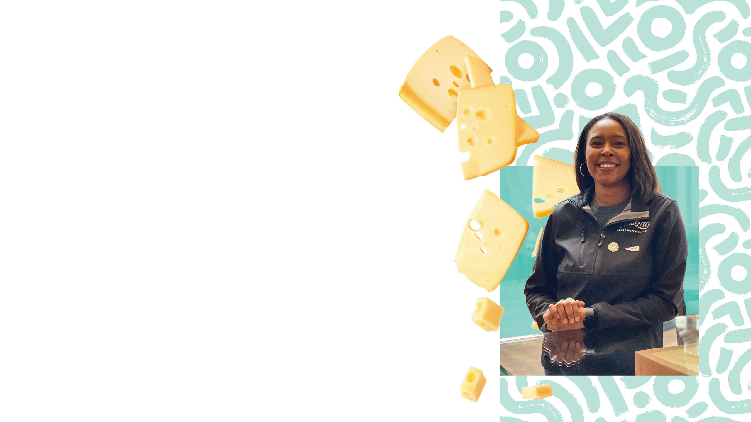 Takiyah Ball, microbiologist at Sargento, smiling at the camera in a black half-zip coat that says Sargento on it. Behind her, large pieces of cheese are tumbling down.
