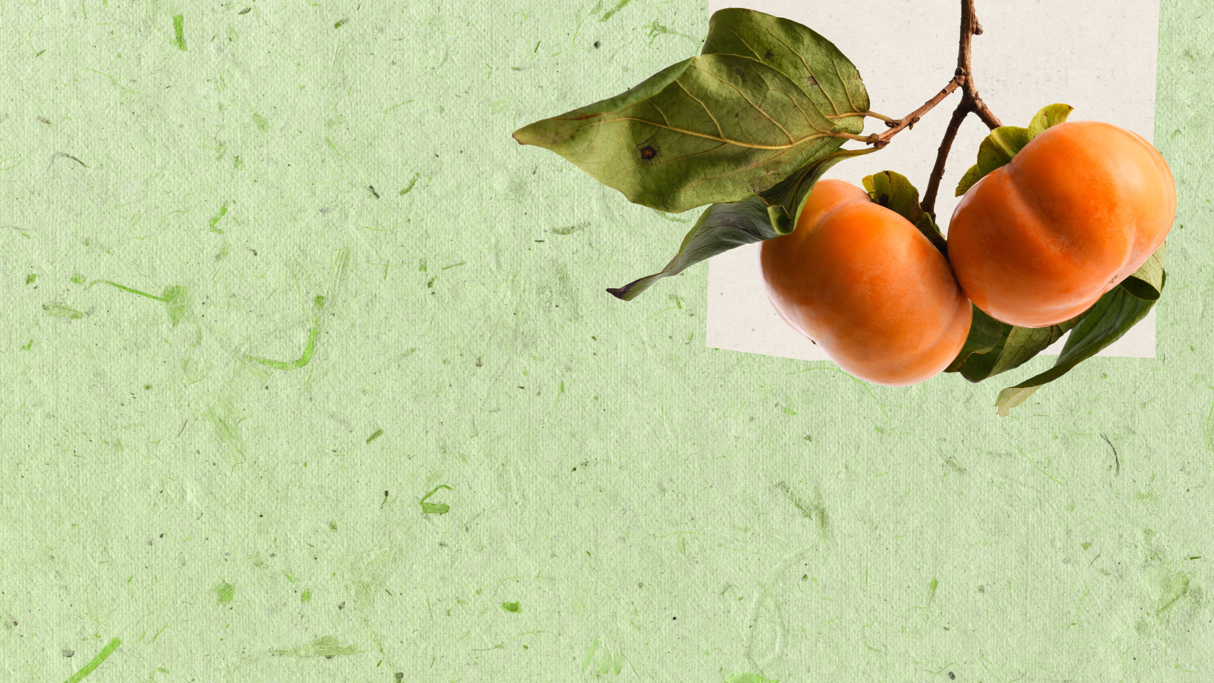 Collage of green paper with natural fibers and a cutout of a persimmon fruit and leaves