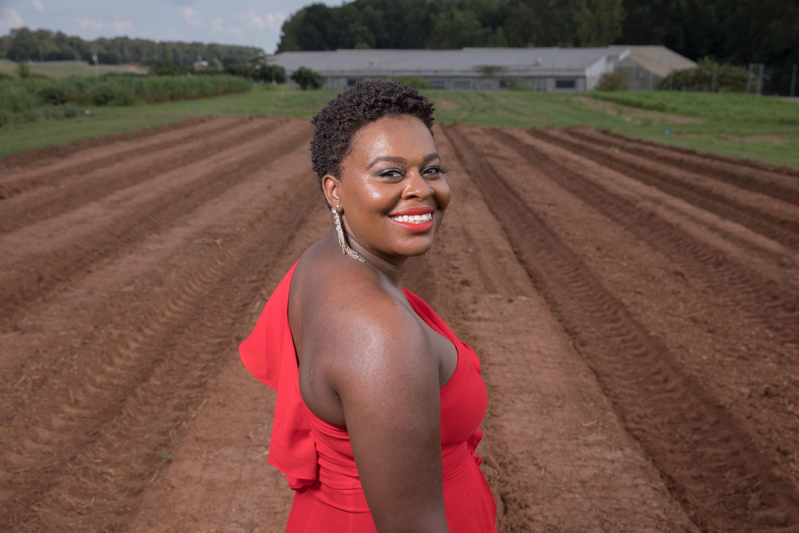 Kristen Dunning looks back at the camera while standing in front of planting rows at UGArden off of UGA's Athens campus.