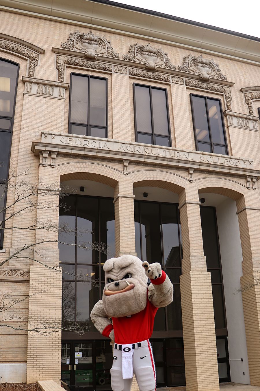 The UGA mascot, Hairy Dawg, poses in front of the CAES building.