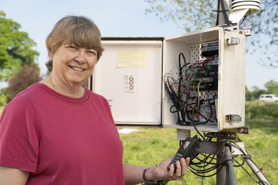 Pam Knox standing next to a weather station open to show the wires inside.